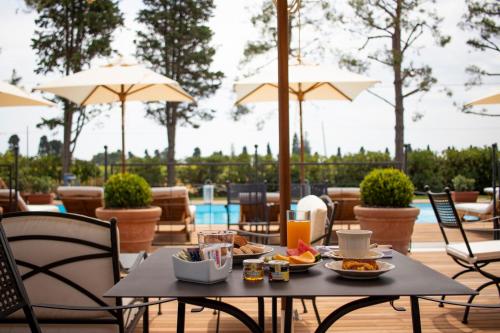 Una mesa con comida de desayuno en un patio con sombrillas. en Casa tua Spa Resort, en Porto Recanati