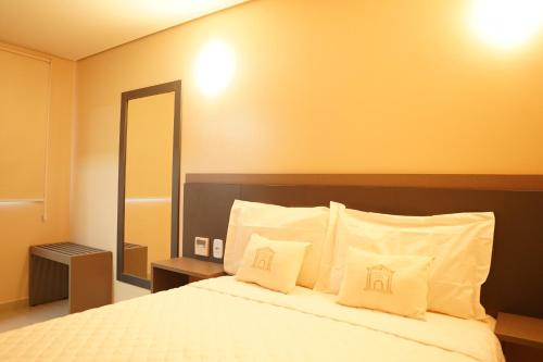 a bedroom with a bed with white pillows and a mirror at Forte Express in Macapá