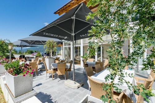 a patio with tables and chairs and an umbrella at Hotel Andy 4 Sterne Superior in Jerzens