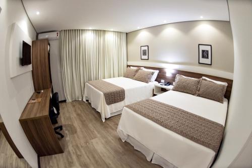 ein Hotelzimmer mit 2 Betten und einem Spiegel in der Unterkunft Villas Hotel in Santo Ângelo