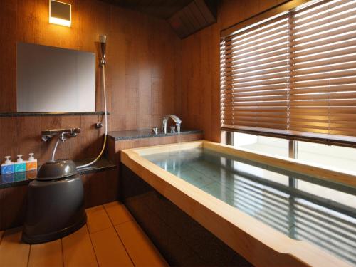 a bathroom with a tub with a sink and a mirror at Asaya in Nikko