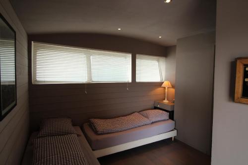 ヴィレンヌ・シュル・セーヌにあるコム アン ポアソン ダン ローのベッド2台と窓が備わる小さな客室です。