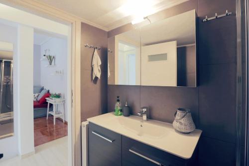 ein Bad mit einem Waschbecken und einem Spiegel in der Unterkunft Bright & Cozy Flat in Central Koukaki in Athen