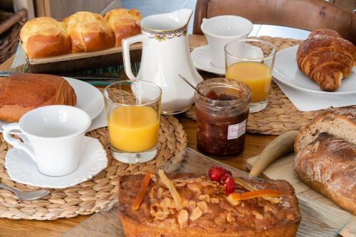 - une table avec petit-déjeuner composé de pain et de jus d'orange dans l'établissement Le Feneau Maison d'hôtes avec jacuzzi, à Creuzier-le-Neuf