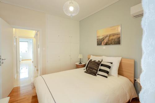 ein weißes Schlafzimmer mit einem großen weißen Bett mit Kissen in der Unterkunft Bright & Cozy Flat in Central Koukaki in Athen