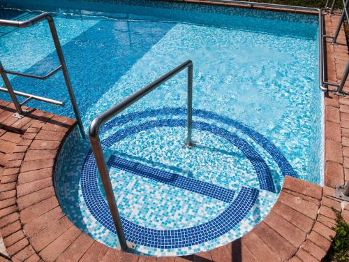 a swimming pool with a spiral staircase in the water at Dunai Gyöngy Vendégház in Kisapostag