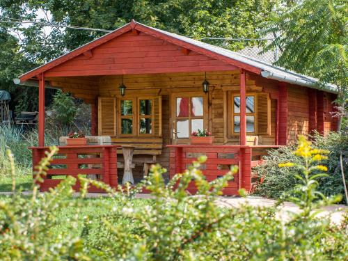 a small wooden cabin with a red roof at Dunai Gyöngy Vendégház in Kisapostag