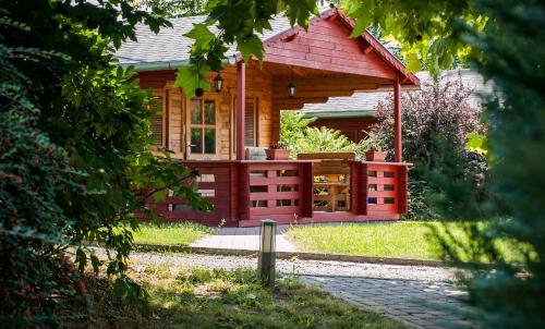 a small wooden cabin with a porch in a yard at Dunai Gyöngy Vendégház in Kisapostag