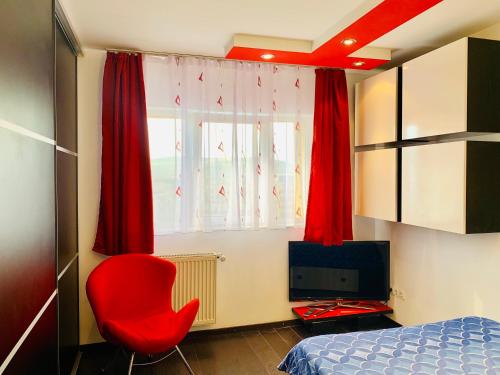 クルジュ・ナポカにあるRed Nest Homestayのベッドルーム(赤い椅子、ベッド、テレビ付)