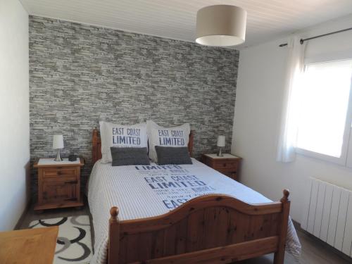 une chambre avec un lit et un mur de briques dans l'établissement petite maison les sables d'olonne, à Les Sables-dʼOlonne
