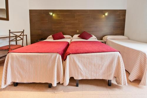 a room with three beds with red and white blankets at Hostal Sol in Toledo