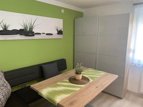 a dining room with a wooden table and green walls at Ferienwohnungen zum Briefmarkenhaus in Mörbisch am See