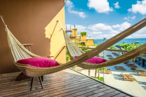 a hammock on a balcony with a view of the ocean at Hotel Xcaret Mexico All Parks All Fun Inclusive in Playa del Carmen