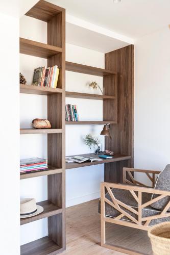 a living room with wooden bookshelves and a chair at Craveiral Farmhouse by Belong Staying & Feeling in São Teotónio