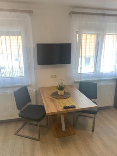a dining room table with chairs and a television on the wall at Ferienwohnungen zum Briefmarkenhaus in Mörbisch am See