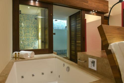 a bathroom with a bath tub with a window at Hotel Xcaret Mexico All Parks All Fun Inclusive in Playa del Carmen