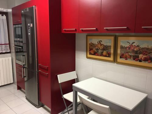 a kitchen with red cabinets and a table and a refrigerator at Precioso piso entre playa y monte in Górliz-Elexalde