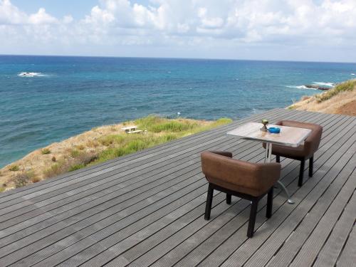 a wooden deck with a table and chairs on the ocean at Beach Villa Pantheon in Pomos