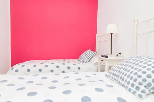 a bedroom with a pink wall and two beds at Hostal Five Gates in Osuna