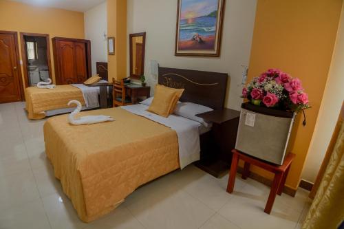 a hotel room with two beds and a swan on a table at Victoria Suites Hotel in Santo Domingo de los Colorados