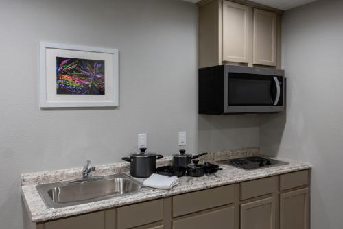 a kitchen with a sink and a stove and a microwave at Budget Inn & Suites Baton Rouge in Baton Rouge