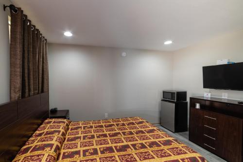 a bedroom with a bed and a flat screen tv at Budget Inn & Suites Baton Rouge in Baton Rouge