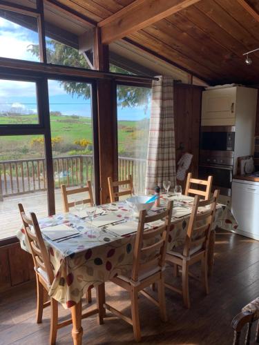 una sala da pranzo con tavolo, sedie e ampia finestra di The Fuschias a Camp