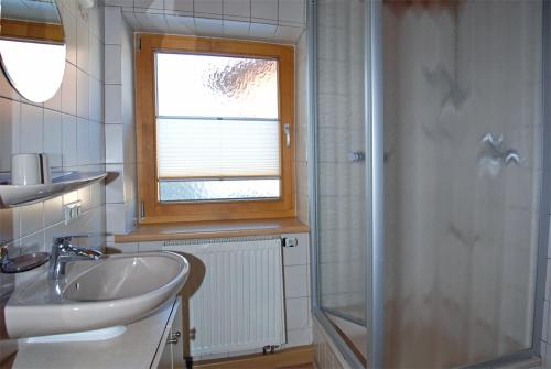 a bathroom with a sink and a window and a shower at Ferienhof Kleber Bauernhof - mit KönigsCard in Seeg