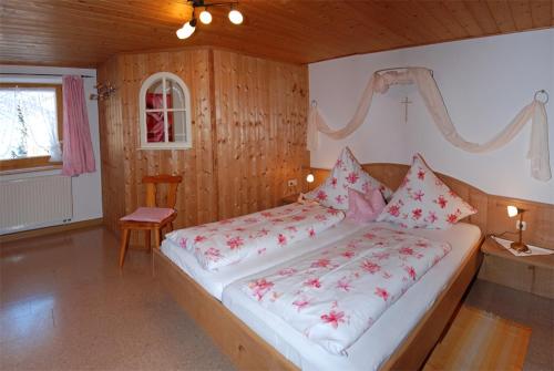 a bedroom with a large bed with red flowers on it at Ferienhof Kleber Bauernhof - mit KönigsCard in Seeg