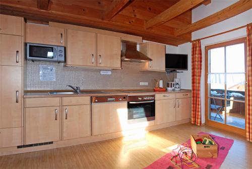 a kitchen with wooden cabinets and a large window at Ferienhof Kleber Bauernhof - mit KönigsCard in Seeg