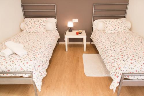 two beds in a small room with a table at Hostal Five Gates in Osuna
