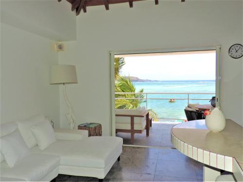 a living room with a white couch and a view of the ocean at Hotel Les Ondines Sur La Plage in Gustavia
