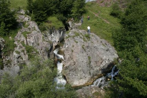 une personne debout au sommet d'une roche à côté d'une cascade dans l'établissement Planinski RaJ - Mountain PaRaDiSe, à Trnovo