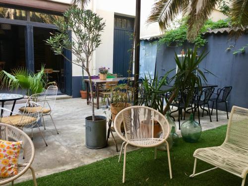eine Terrasse mit Stühlen, Tischen und Pflanzen in der Unterkunft Les Cagettes en Ville in Perpignan