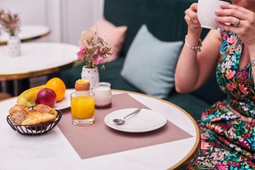 a woman taking a picture of a table with breakfast food at Mercure Nantes Centre Passage Pommeraye in Nantes