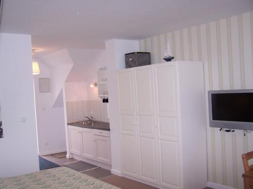 a kitchen with white cabinets and a tv on a wall at Nowe Guty Fun in Nowe Guty