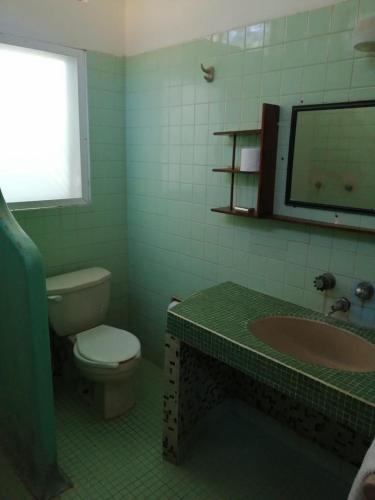 a green bathroom with a toilet and a sink at Bungalows pacíficos in Zihuatanejo