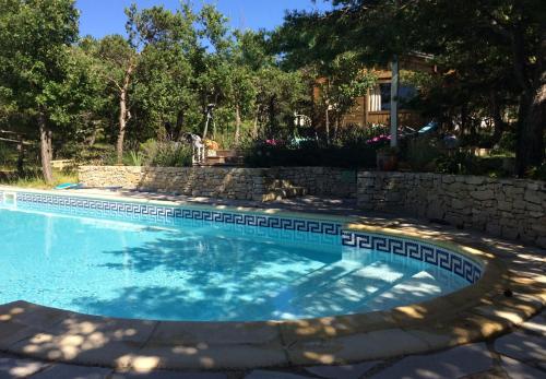 a swimming pool in a yard with a stone wall at Le Mapillon in Dieulefit