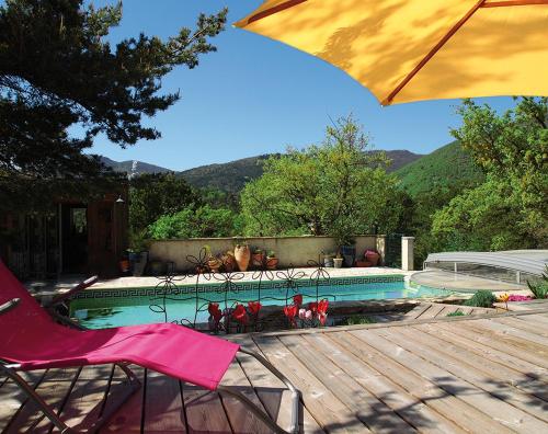 una sedia e un ombrellone accanto alla piscina di Le Mapillon a Dieulefit