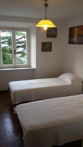 two beds in a room with two windows at La Casalina dell'Elba in Marciana