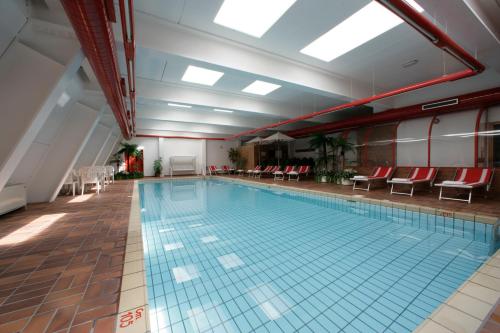 a large swimming pool in a building with red chairs at Hotel Garni Gonzaga in Canazei