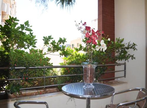 a glass table with a vase of flowers on a balcony at Nest 1 Hotel in Beirut