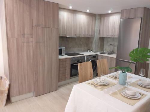 uma cozinha com armários de madeira e uma mesa e cadeiras brancas em Apartamentos Vacacionales Joctis, 2º B em Fuengirola