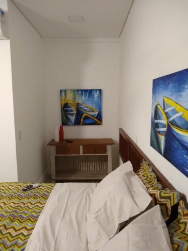 a bedroom with a bed and two paintings on the wall at Suítes Km18praia in Barra do Una