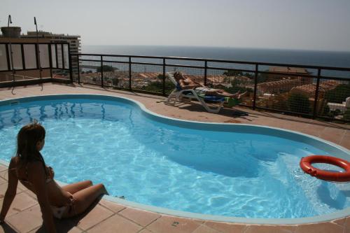 a girl sitting in a swimming pool with the ocean in the background at Apartahotel Aguadulce in Aguadulce