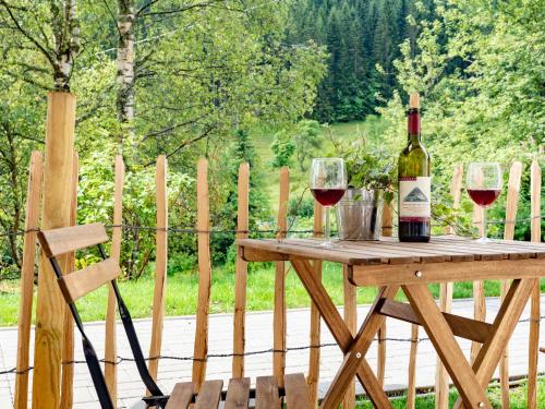a bottle of wine and two glasses on a wooden table at Black Forest Apartements by Hotel Grüner Baum Feldberg in Feldberg