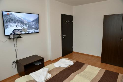a bedroom with a bed with a flat screen tv on the wall at Iglika 2, V9 in Borovets