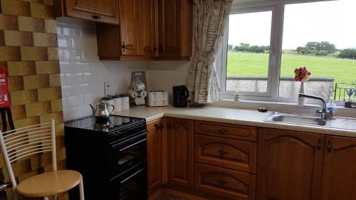 eine Küche mit einer Spüle, einem Herd und einem Fenster in der Unterkunft Tornabodagh House in Ballycastle