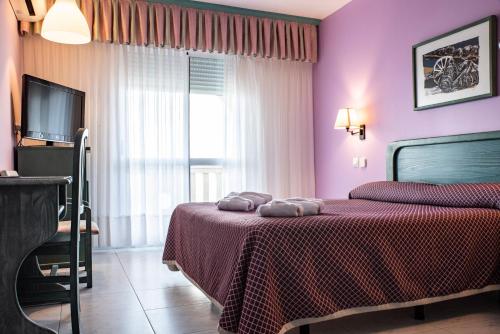 a bedroom with a bed with purple walls and a television at Hotel Torre Cristina in Noja
