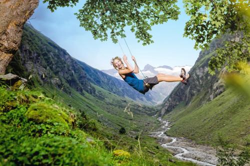 a woman swinging on a rope swing over a valley at Wanderhotel Kirchner in Bramberg am Wildkogel